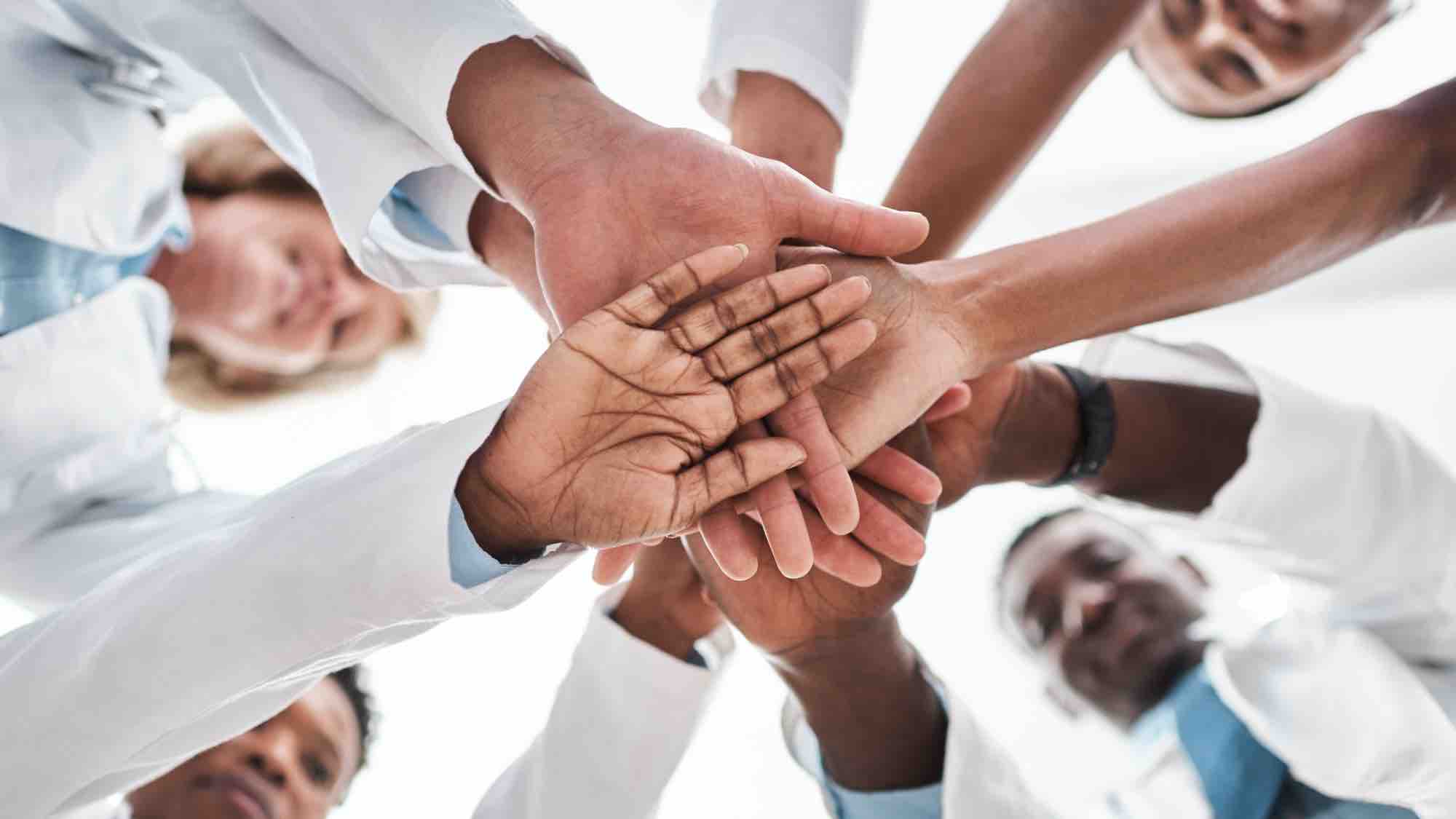 circle of people holding their hands together in the center, photographed from below