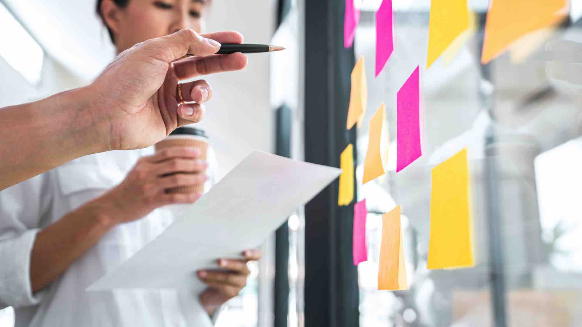 people standing in front of a glass wall with post-it notes