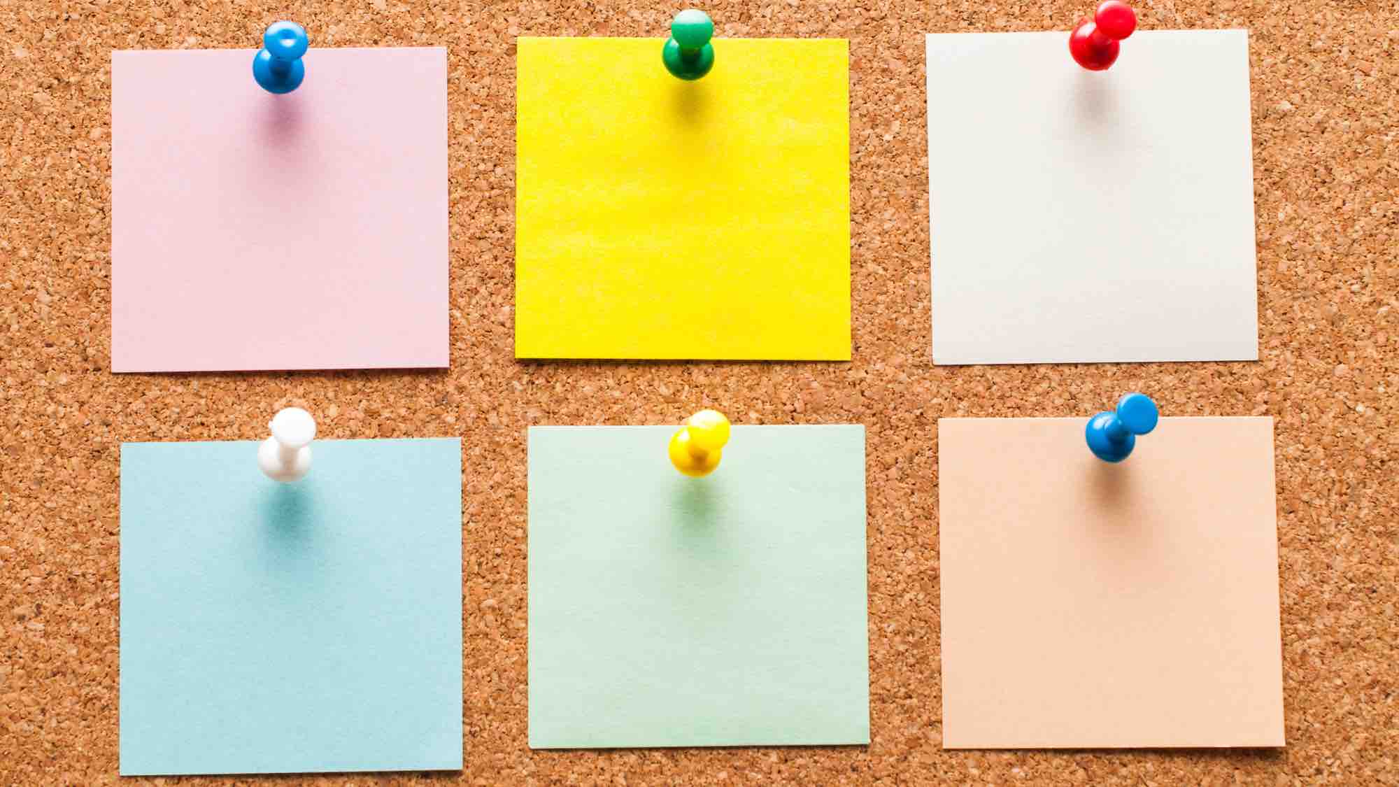 Six square post-it notes on a cork board.