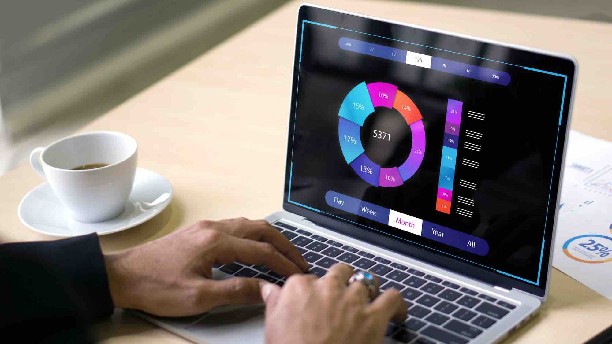 Close up of person at laptop computer typing. A circular graphic with numbers on it is displayed on the computer.